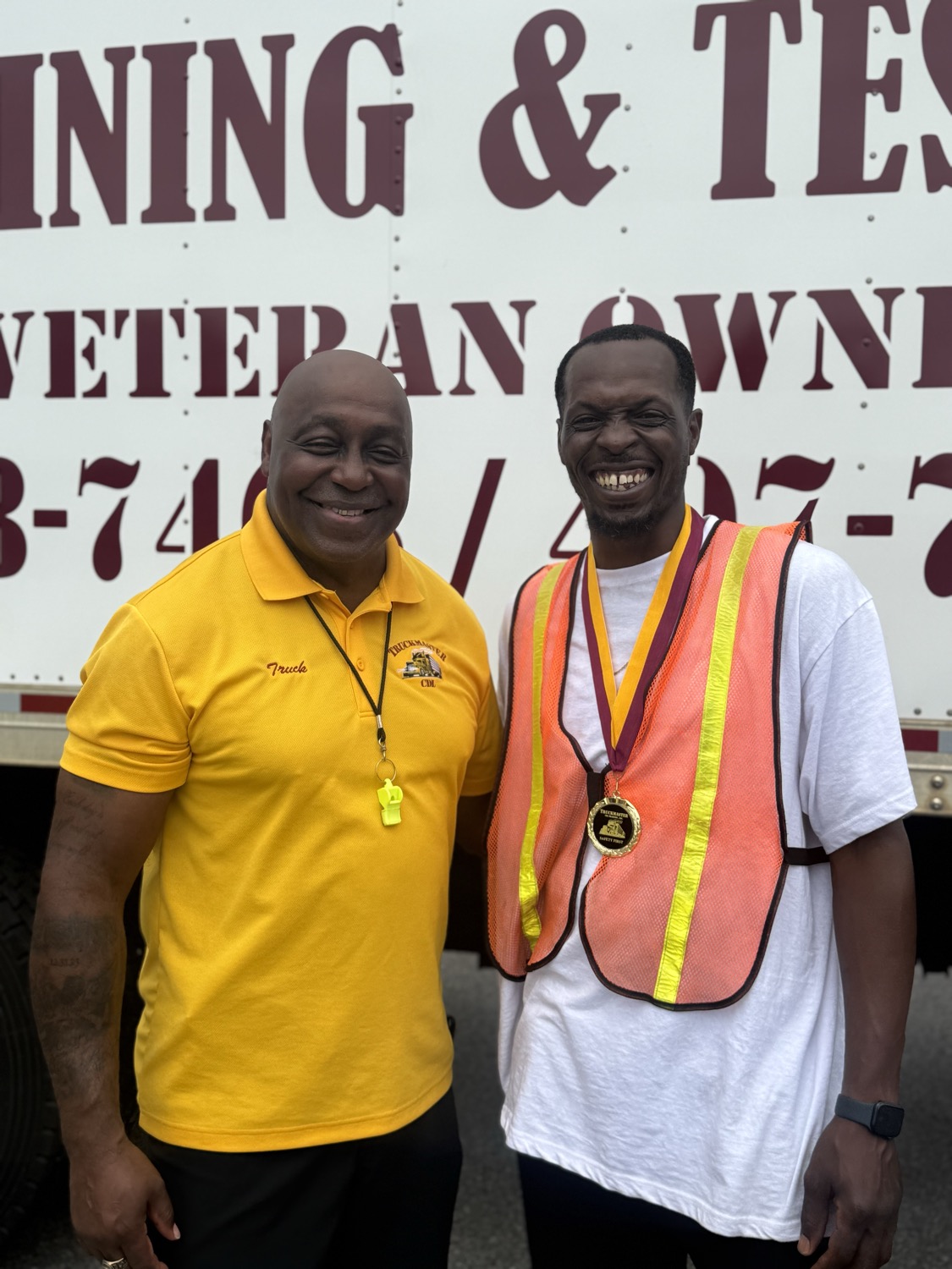 Owner Byron Simpson celebrating with a smiling TruckMaster CDL graduate wearing a Safety First medal