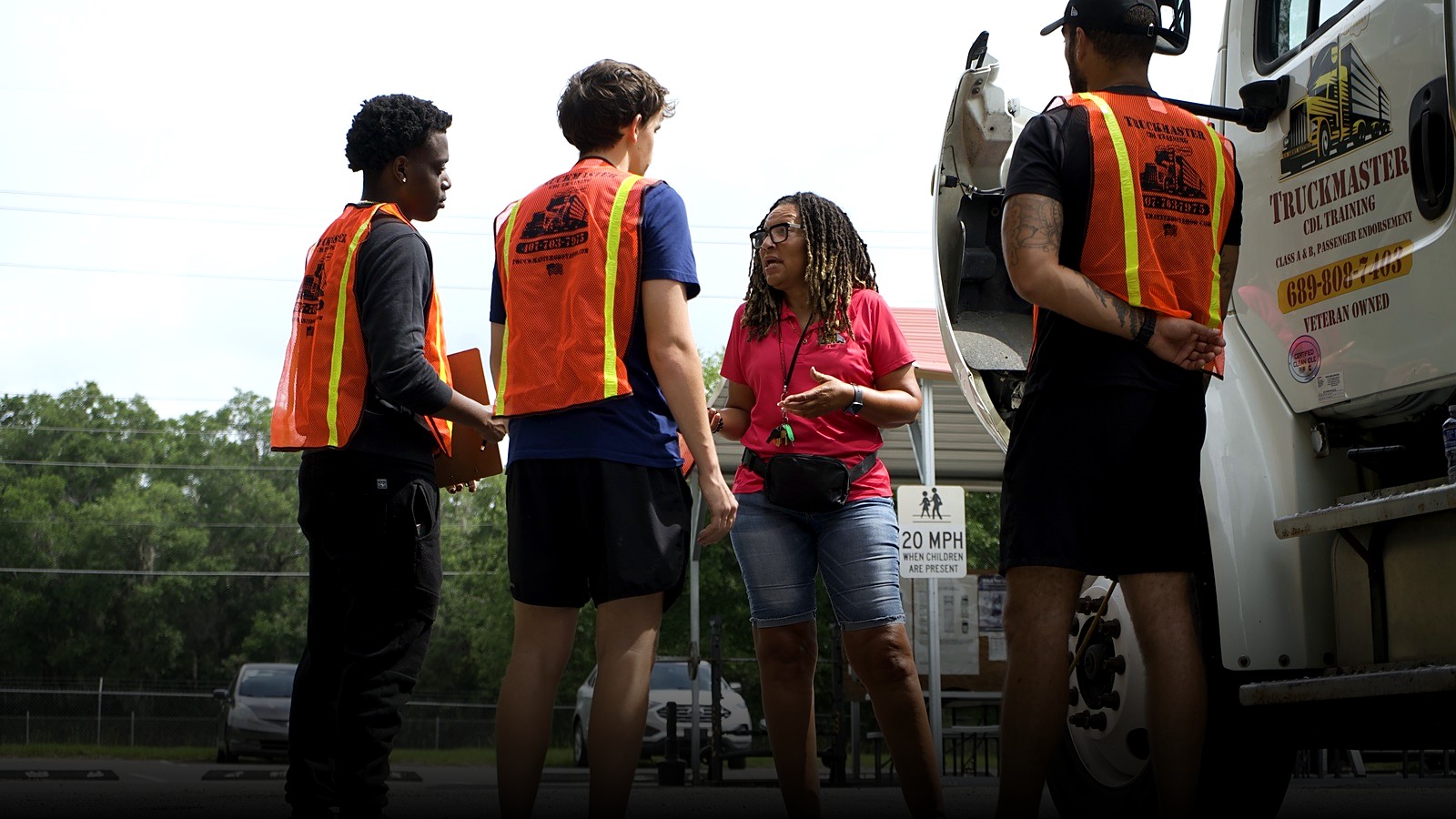 TruckMaster CDL instructor Channel coaching students in safety vests beside a TruckMaster training truck in Apopka, FL