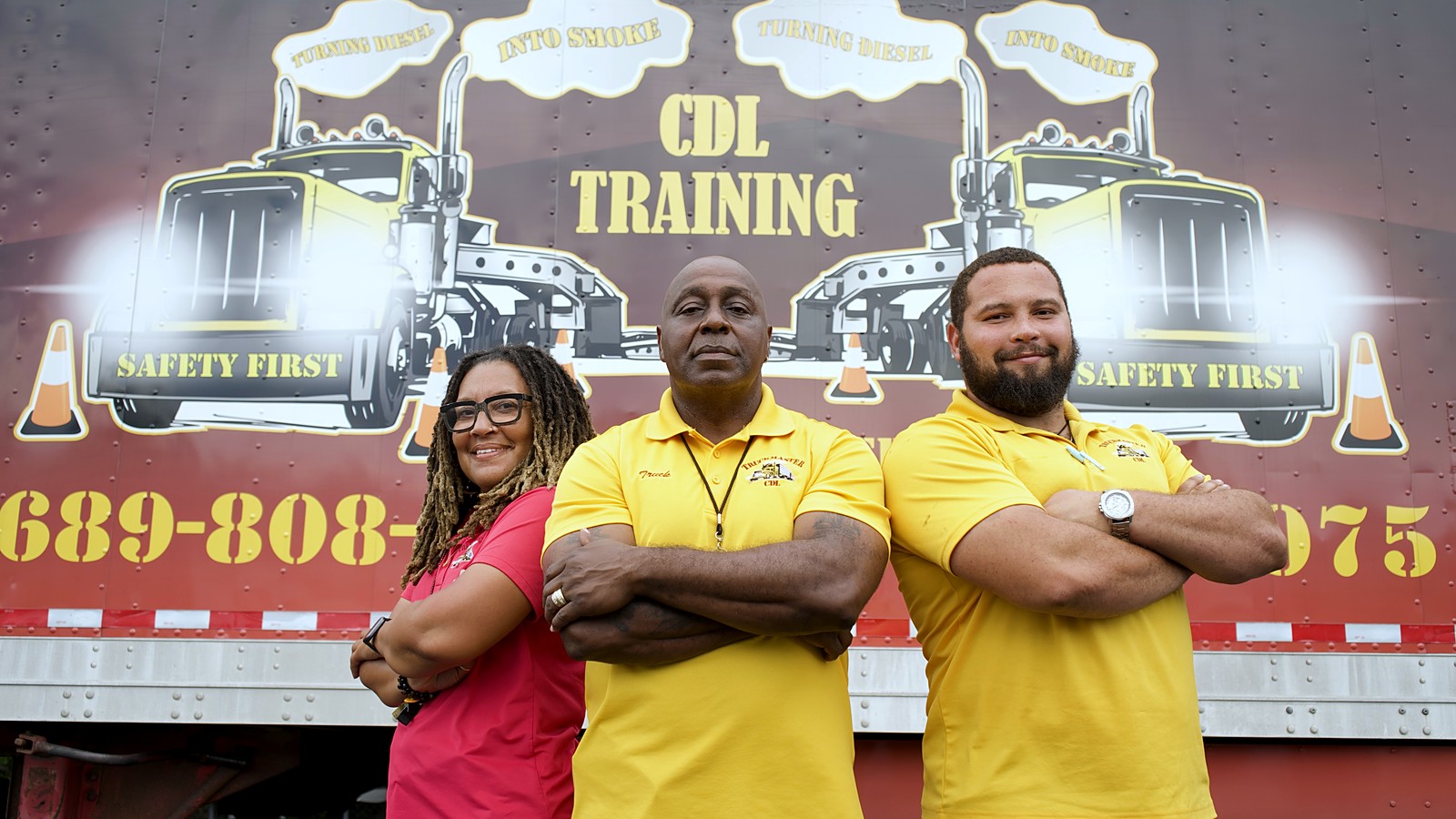 The TruckMaster CDL team — instructors Channel and Ashanti with owner Byron Simpson in front of the TruckMaster training trailer in Apopka, FL