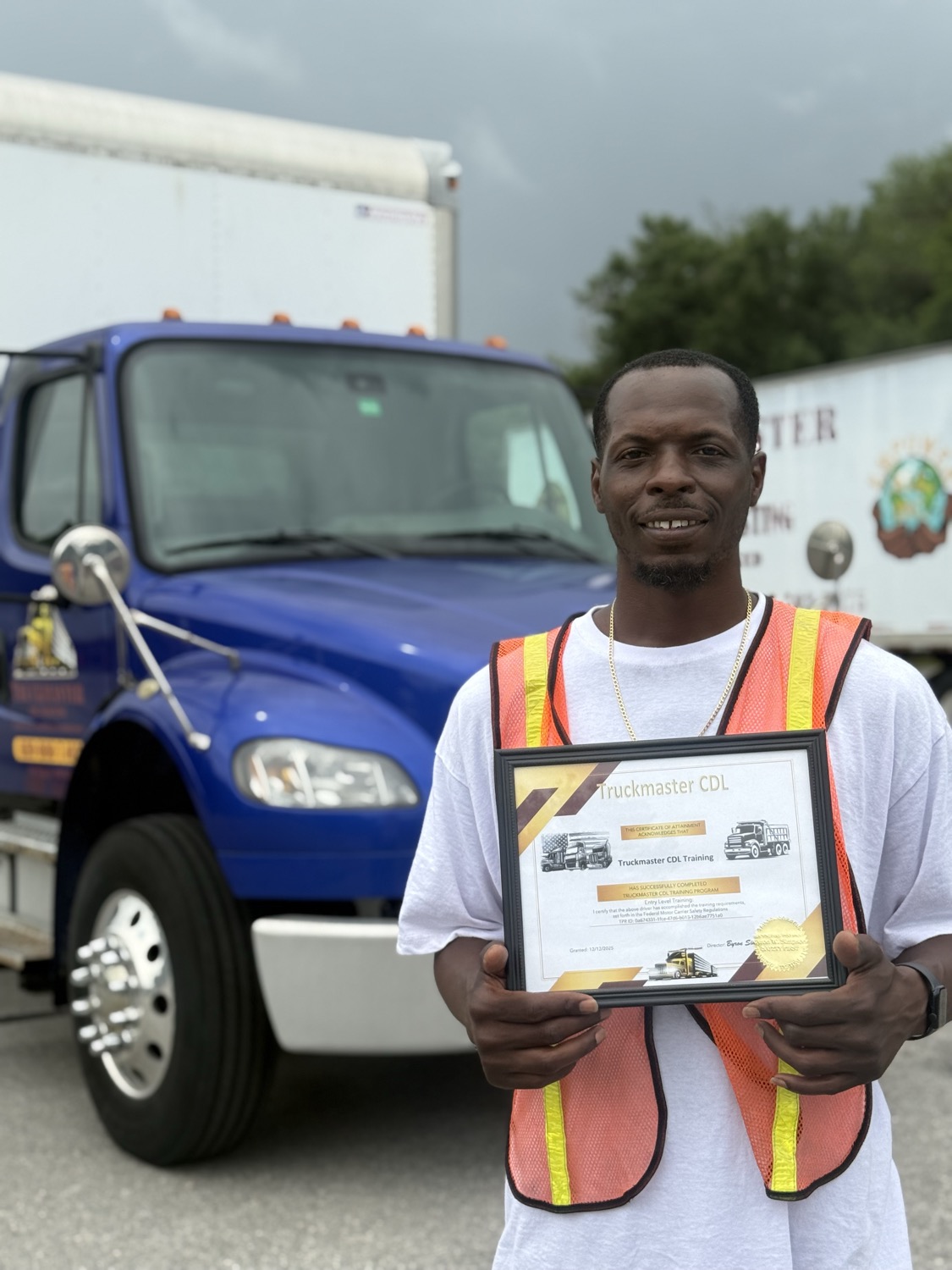 TruckMaster CDL graduate holding his completion certificate in front of a training truck