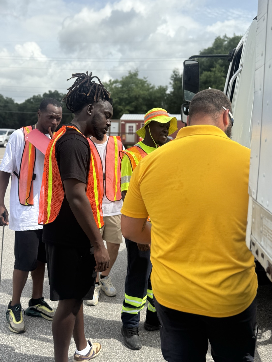 TruckMaster instructor coaching a group of CDL students in safety vests beside a truck